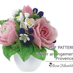 Puede incluir: Un patrón PDF para un arreglo floral de cuentas llamado "Provenza". El arreglo presenta rosas rosadas, flores blancas y bayas azules en una maceta blanca.
