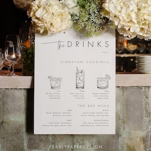 Puede incluir: Un menú de bar blanco con el texto "The Drinks" y "Signature Cocktails" exhibido en una barra. El menú presenta ilustraciones de cócteles y una lista de bebidas. Un arreglo floral de hortensias blancas y azules se encuentra encima del menú.