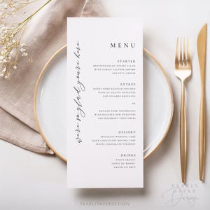 May include: A white wedding menu card with black text. The menu includes starter, entree, dessert, and drinks. The text reads: "We're so glad you're here."  "MENU"  "STARTER"  "MEDITERRANEAN TOSSED SALAD WITH GARLIC SAUTEED SHRIMP AND FETA CHEESE"  "ENTR&Eacute;E"  "HONEY HERB ROASTED CHICKEN WITH AU GRATIN POTATOES AND STEAMED BROCCOLI OR GRILLED PORK TENDERLOIN WITH ROASTED NEW POTATOES AND ROSEMARY VEGETABLES"  "DESSERT"  "SPECIALTY WEDDING CAKE DARK CHOCOLATE MOUSSE CAKE WHITE CHOCOLATE TIRAMISU"  "DRINKS"  "PINOT GRIGIO C&Ocirc;TES DU RH&Ocirc;NE PROSECCO BRUT"  "PEARLYPAPERDESIGN"