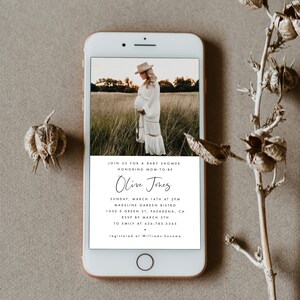 May include: A white and black baby shower invitation with a photo of a pregnant woman in a white dress and a hat. The invitation includes the text "Join us for a baby shower honoring mom-to-be Olive Jones" and details about the event.
