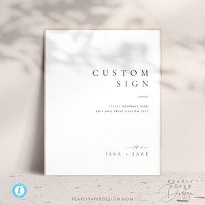 May include: A white sign with black text that reads "CUSTOM SIGN" and "11x14 PORTRAIT SIGN EDIT AND PRINT CUSTOM TEXT". Below the text is a line and the text "with love ISSA + JAKE".