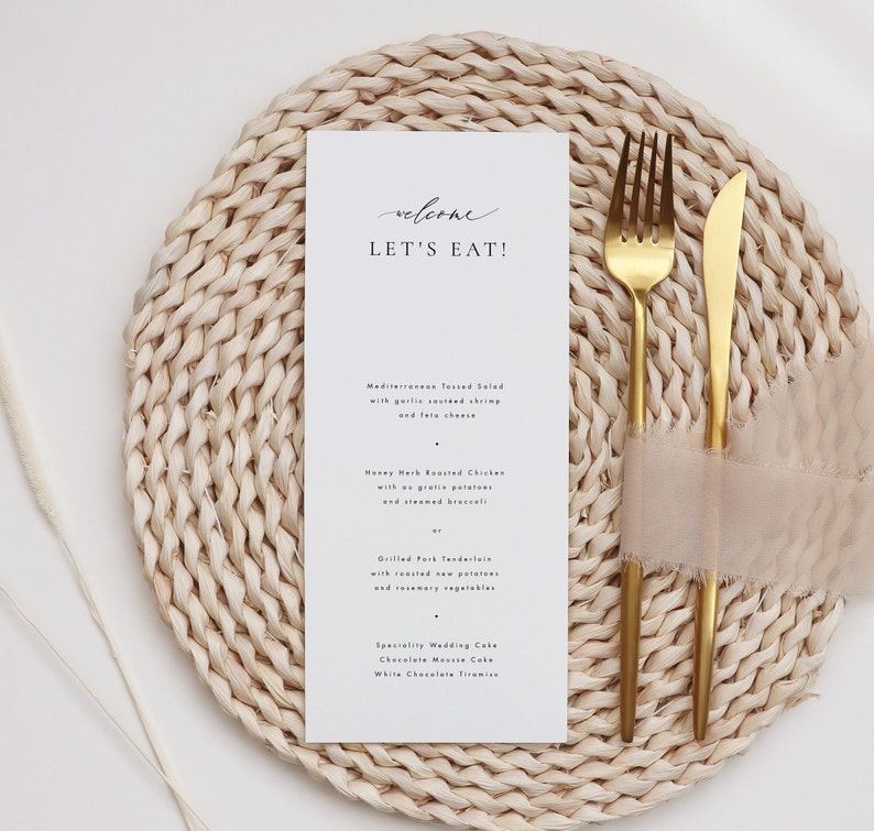 May include: A white card with the text "welcome let's eat!" on a woven placemat with gold silverware and a pink napkin. The menu includes Mediterranean Tossed Salad, Honey Herb Roasted Chicken, Grilled Pork Tenderloin, and Specialty Wedding Cake.