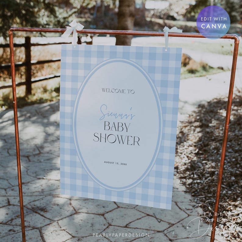May include: A baby shower sign with a blue gingham pattern background. The sign reads "Welcome to Sienna's Baby Shower" in elegant script. The sign is displayed on a copper-colored metal stand and is decorated with white ribbons.