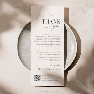 Op de afbeelding: Een bedankkaart met een eenvoudig zwart-wit ontwerp. De kaart bevat de tekst "Bedankt" in een handschrift en de woorden "Lieve familie en vrienden" in een sans-serif lettertype. De kaart bevat ook een QR-code en de tekst "We zouden graag onze speciale dag door jouw ogen zien. Scan om je foto's en video's met ons te delen."