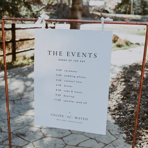 Puede incluir: Un cartel blanco con texto negro que enumera el orden de los eventos de una boda. El cartel est&aacute; colgado de un marco de tuber&iacute;a de cobre. El texto dice: "THE EVENTS ORDER OF THE DAY 4:00 ceremony 5:00 wedding photos 5:30 cocktail hour 6:30 dinner 8:00 cake & toasts 9:00 dancing 11:00 sparkler send off CELINE & MATEO 08.21.2021 Balcoart Castle"