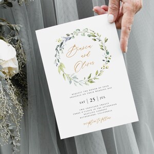 May include: A wedding invitation with a watercolor wreath of green leaves and white flowers. The invitation is for Bianca and Oliver's wedding on Saturday, July 25th at 3:00 PM at Beaulieu Gardens in Rutherford, California.