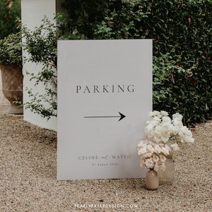 May include: A white sign with black text that reads "Parking" with a black arrow pointing to the right. Below the arrow, it says "Celine and Mateo 21 August 2020".