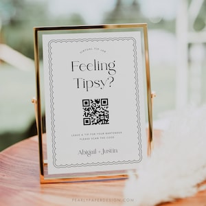May include: A white sign with a gold frame, featuring a black and white QR code and the text "Feeling Tipsy?"  Leave a tip for your bartender, please scan the code. Abigail + Justin. Pearlypaperdesign.com.
