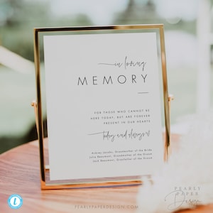 Pode incluir: Um cartaz branco em uma moldura dourada com o texto "in loving memory" e uma mensagem para aqueles que não podem estar presentes no casamento. O cartaz também inclui os nomes dos entes queridos falecidos: Aubrey Jacobs, Julie Beaumont e Jack Beaumont.