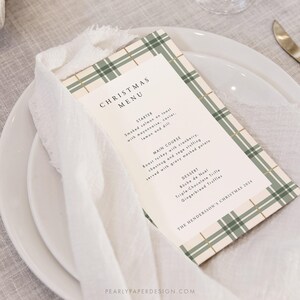 May include: A Christmas menu card with a green and white plaid pattern. The menu includes starter, main course, and dessert options. The text reads "Christmas Menu", "Starter", "Smoked salmon on toast with mayonnaise, caviar, lemon and dill", "Main Course", "Roast turkey with cranberry, chestnut and sage stuffing served with gravy mashed potato", "Dessert", "B&uuml;che de No&euml;l", "Triple-Chocolate Trifle", "Gingerbread Truffles", and "The Henderson's Christmas 2024".
