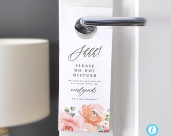 Puede incluir: Un colgador de puerta blanco con diseño floral rosa y melocotón. El texto dice "Jkkk! Por favor, no molestar. Bailamos y festejamos toda la noche con los recién casados. Sr. y Sra. Andrews."