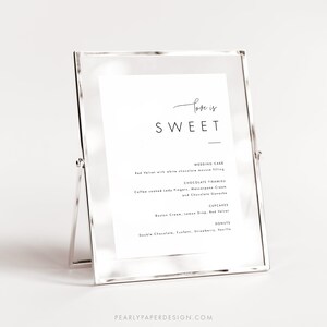 Puede incluir: Un cartel enmarcado en plata con el texto "Love is Sweet" en la parte superior. El cartel enumera varias opciones de postres, que incluyen pastel de bodas, tiramis&uacute; de chocolate, cupcakes y donas.