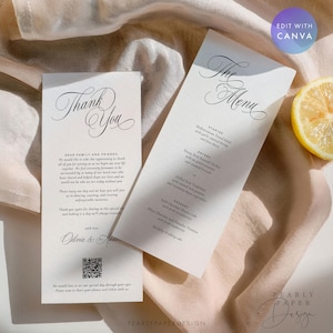Może przedstawiać: Dwie pionowe białe karty papierowe z czarnym, eleganckim tekstem pisanym kursywą. Jedna karta zatytułowana jest Thank You z kodem QR na dole, a druga The Menu, wymieniająca przystawki, dania główne i desery. Widoczny jest plasterek cytryny.