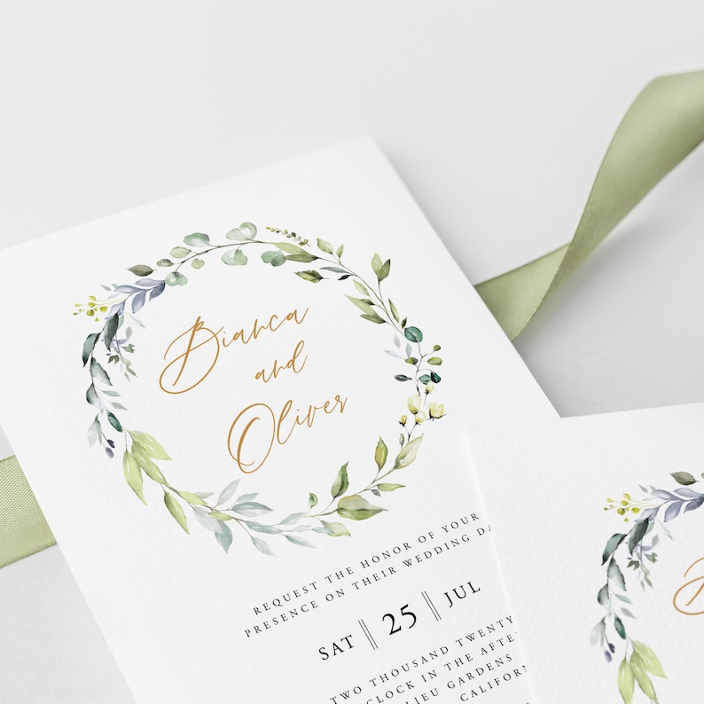 May include: A wedding invitation with a watercolor wreath of green leaves and white flowers. The text "Diarca and Oliver" is written in gold script. The date "SAT || 25 || JUL" is printed below the wreath.