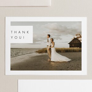 Puede incluir: Una tarjeta de agradecimiento de boda con una foto de una novia y un novio de pie en una playa. El texto "THANK YOU!" est&aacute; en un cuadro blanco en el lado izquierdo de la tarjeta.