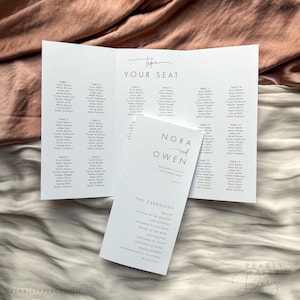 May include: A wedding seating chart with the names Nora and Owen at the top. The chart lists tables with guest names. The ceremony order is listed on a separate card.