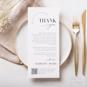 Op de afbeelding: Een witte bedankkaart met zwarte tekst. De kaart zegt "We're so glad you're here" in een cirkel bovenaan. De tekst "Thank you" staat in een groot lettertype met een handgeschreven "you". De kaart bevat ook een QR-code en de tekst "We would love to see our special day through your eyes. Please scan to share your photos and videos with us." onderaan.