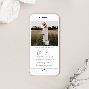 May include: A white and gold phone screen displaying a baby shower invitation for Olive Jones. The invitation includes the date, time, location, and RSVP information. A photo of a pregnant woman in a white dress is in the background.