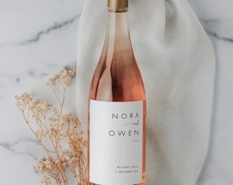 May include: A pink wine bottle with a white label that says "Nora and Owen" with the date "7 September 2020" and the location "Belcourt Castle".
