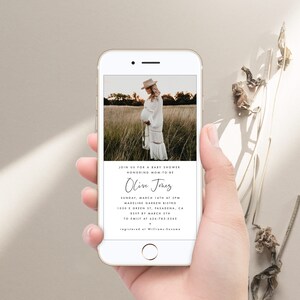 May include: A white smartphone screen displays a baby shower invitation for Olive Jones. The invitation includes the date, time, location, and RSVP information. A photo of a pregnant woman in a white dress is in the background.