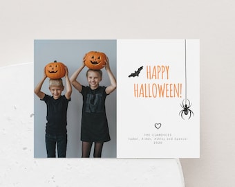 May include: A Halloween card with a photo of two children holding jack-o'-lanterns. The card says "Happy Halloween!" with a bat and spider graphic. The text at the bottom reads "The Clarences, Isabel, Aiden, Ashley and Spencer, 2020."