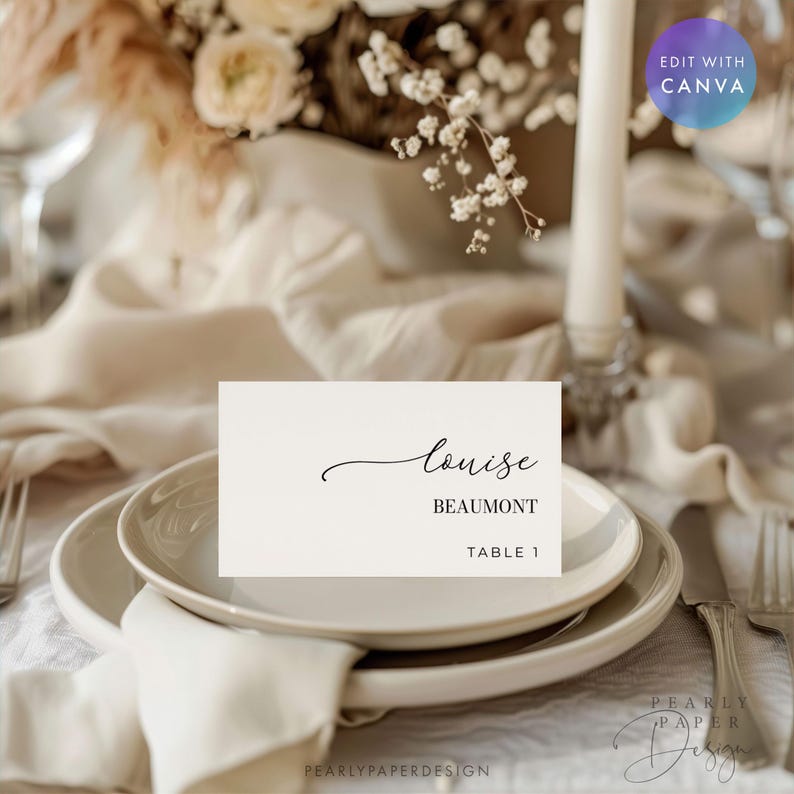 May include: A place setting with a white card featuring the name "Louise" in elegant script, with "Beaumont" below. The card is on a white plate, with a napkin and silverware. The background includes flowers and a candle.