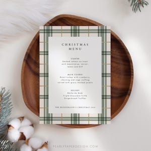 May include: A Christmas menu card with a green and white plaid pattern and gold accents. The menu includes starter, main course, and dessert options. The text reads "Christmas Menu", "Starter", "Smoked salmon on toast with mayonnaise, caviar, lemon and dill", "Main Course", "Roast turkey with cranberry, chestnut and sage stuffing served with gravy mashed potato", "Dessert", "B&ucirc;che de No&euml;l", "Triple-Chocolate Trifle", "Gingerbread Truffles", and "The Henderson's Christmas 2024".