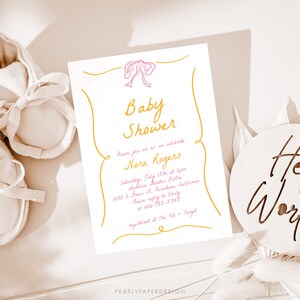 May include: A white baby shower invitation with a pink bow and gold lettering. The invitation reads "Baby Shower" and "Please join us as we celebrate Nora Rogers". The invitation also includes the date, time, location, and RSVP information.