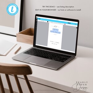 May include: A laptop displaying a wedding invitation template with the words "Let Love Sparkle." The design includes the names Issa and Jake, along with the date 09.23.22. The laptop is on a white desk with a wooden box and a pen.