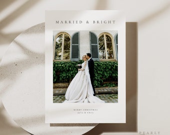 May include: A Christmas card featuring a photograph of a newly married couple standing in front of a building with windows. The text "Married & Bright" is at the top of the card and "Merry Christmas Julie & Chris" is at the bottom.
