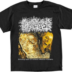 May include: Black t-shirt with a white band logo that says "Autopsy" and a graphic of two yellow and white faces. The text "Grinding Opus Of Forensic Medical Problems" is printed below the graphic.