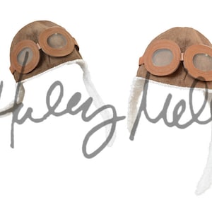 May include: Two brown faux leather aviator hats with faux fur trim and goggles. The hats are on a white background.