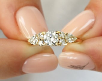 May include: A gold engagement ring with a large round center diamond and smaller pear-shaped diamonds on either side.
