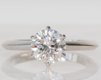 May include: A silver ring with a large, round, clear diamond.
