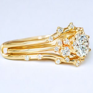 May include: A gold ring with a large, round diamond surrounded by smaller diamonds. The ring band is made of three thin bands of gold that are intertwined.