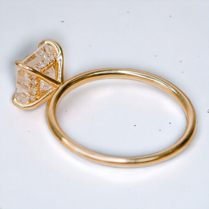 Puede incluir: Un anillo de oro con un gran diamante de forma cuadrada engastado en garras. El diamante est&aacute; rodeado de diamantes m&aacute;s peque&ntilde;os.