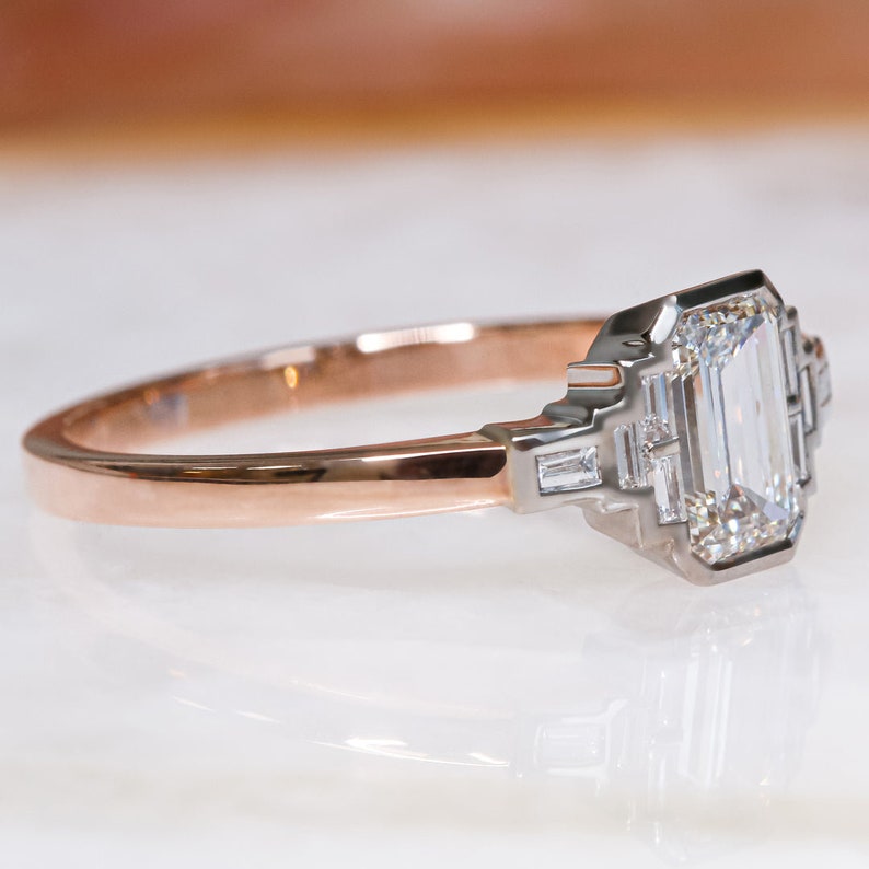 Puede incluir: Un anillo de compromiso de oro rosa con un diamante cuadrado de talla esmeralda y diamantes baguette m&aacute;s peque&ntilde;os en la banda.
