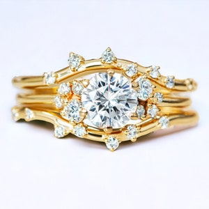 May include: A gold ring with a large, round, clear diamond in the center. The ring is set with smaller diamonds around the center stone and along the band. The ring is made of multiple bands that are intertwined.