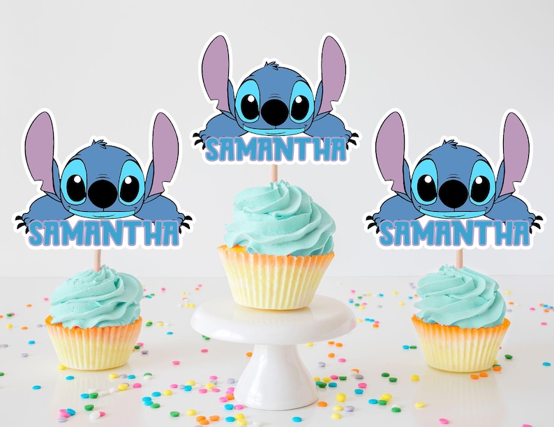K&ouml;nnte beinhalten: Drei blaue und wei&szlig;e Stitch-Cupcake-Topper mit dem Namen Samantha auf jedem. Die Topper befinden sich auf Cupcakes mit hellblauem Frosting.