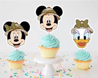 Può includere: Tre cupcake con glassa blu e pirottini gialli. Ogni cupcake ha un topper con un personaggio: Topolino, Minnie Mouse e Paperina. I personaggi indossano cappelli da safari e hanno uno stile da cartone animato.