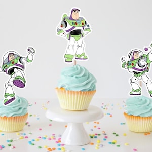 May include: Three cupcakes decorated with Buzz Lightyear from Toy Story. Each cupcake has a different pose of Buzz Lightyear on a cocktail stick.