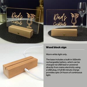 May include: A wooden sign with a warm white light illuminates the text "Dad's Cocktails" and a cocktail glass icon. The sign is powered by a rechargeable battery and can be charged via USB.