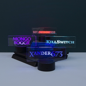May include: Four illuminated acrylic signs with different names on them. The signs are on black bases and are lit up in different colours. The names on the signs are "MONGO BOGGIE", "SGT.CRISBONESS99", "KILLSWITCH", and "XANDER673".