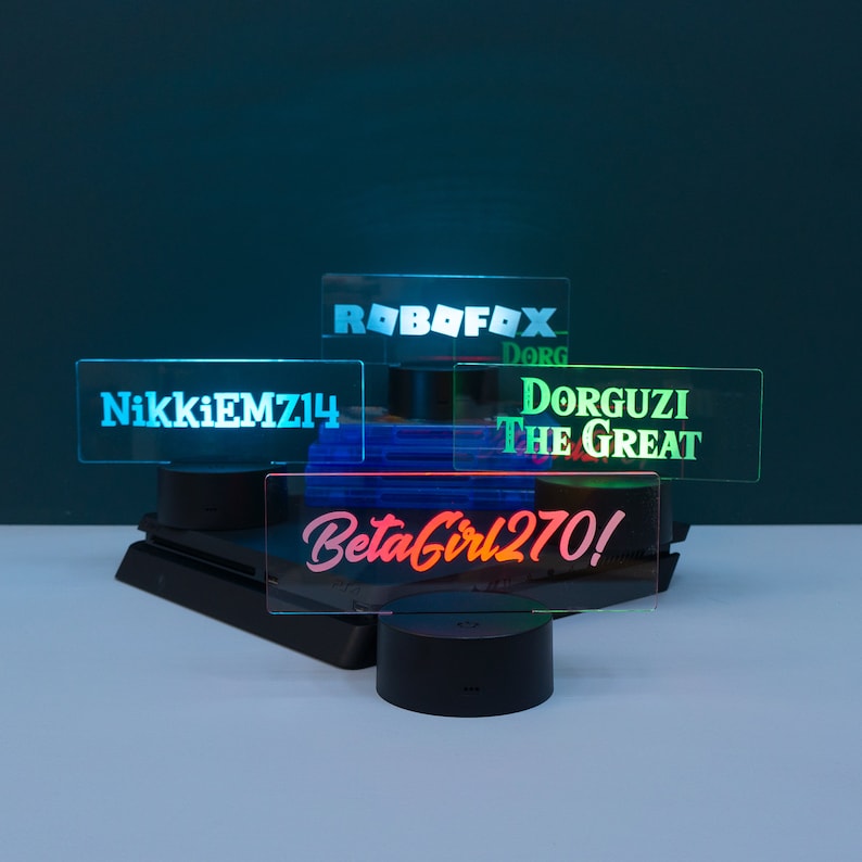 May include: Four acrylic signs with custom text on each. The signs are lit from behind with LED lights. The text on the signs reads "RoboFox", "NikkiEMZ14", "Dorguzi The Great", and "BetaGirl270!"