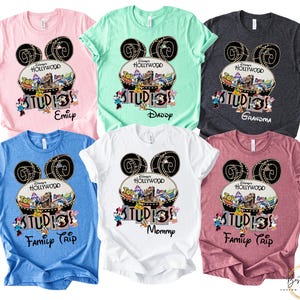 May include: Assorted-color t-shirts featuring a Disney's Hollywood Studios design. Each shirt has a Mickey Mouse ear design with the text "Hollywood Studios" and a family member's name or phrase like "Family Trip".