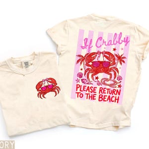 K&ouml;nnte beinhalten: Zwei elfenbeinfarbene T-Shirts mit Krabbenmotiven. Eines hat eine kleine Krabbe auf der Vorderseite. Das andere hat eine gr&ouml;&szlig;ere Krabbengrafik auf der R&uuml;ckseite mit dem Text "If Crabby Please Return to the Beach."