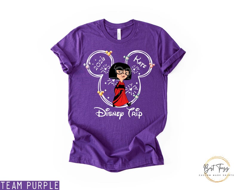 May include: A purple t-shirt featuring a cartoon character in a red dress and black glasses, inside a Mickey Mouse head outline. The text "2020" and "Kate" are inside the ears, with "Disney Trip" below the character.