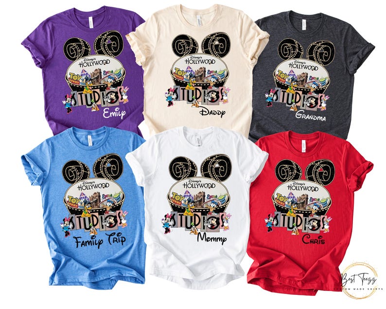 May include: A collection of colorful t-shirts featuring a Disney's Hollywood Studios design. Each shirt has a unique color and personalized text, including names like "Emily," "Daddy," and "Grandma." The design includes Mickey Mouse ears and cartoon characters.