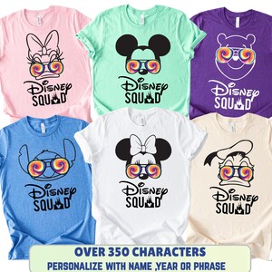 Puede incluir: Seis camisetas coloridas con personajes de Disney con gafas de sol tie-dye. Cada camiseta tiene la frase "Disney Squad" impresa debajo de la imagen del personaje. Las camisetas son de varios colores, incluyendo rosa, azul, verde, blanco, morado y beige.