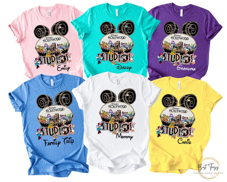 May include: A collection of colorful t-shirts featuring a Disney's Hollywood Studios design. Each shirt has a unique name printed below the graphic, including "Emilp", "Daddy", "Grandma", "Family Trip", "Mommy", and "Chris". The shirts are in various colors, including pink, teal, purple, blue, white, and yellow.